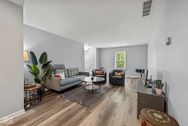 living room with visible vents, baseboards, and wood finished floors
