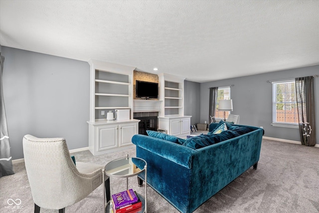 carpeted living area with a textured ceiling, built in features, baseboards, and a fireplace