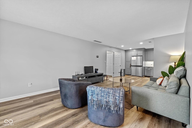 living room featuring light wood-type flooring, recessed lighting, baseboards, and visible vents