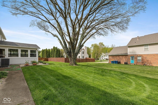 view of yard with a sunroom, central AC unit, and fence