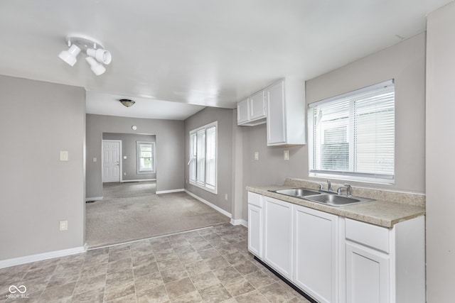 kitchen featuring baseboards, a sink, white cabinetry, and light countertops