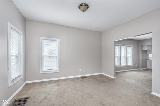 empty room featuring carpet floors, baseboards, and visible vents