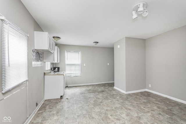 kitchen featuring white cabinets, baseboards, and light countertops