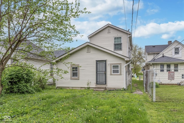 back of property featuring a lawn and fence