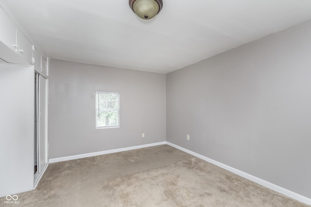 unfurnished bedroom featuring baseboards, light carpet, and a closet