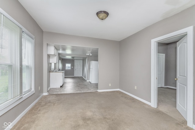 interior space with baseboards and light carpet