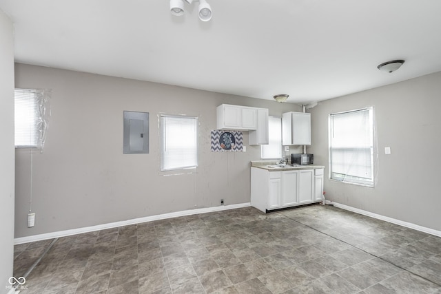 kitchen with a healthy amount of sunlight, white cabinets, and electric panel