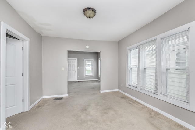 carpeted empty room featuring baseboards and visible vents