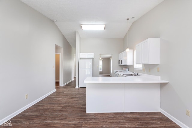 kitchen with freestanding refrigerator, a peninsula, baseboards, and dark wood finished floors