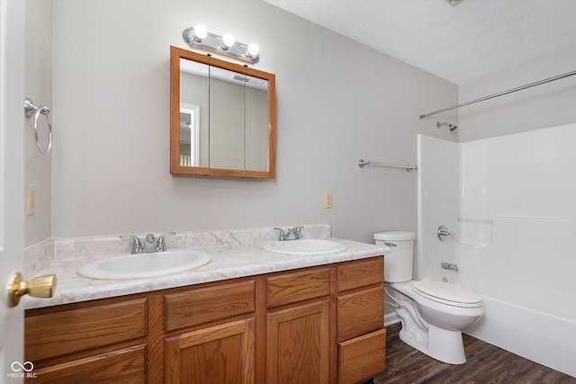 full bath with double vanity, toilet, a sink, and wood finished floors