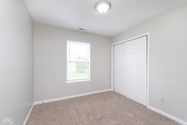 unfurnished bedroom featuring carpet floors, baseboards, visible vents, and a closet