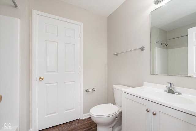 bathroom featuring walk in shower, wood finished floors, vanity, baseboards, and toilet