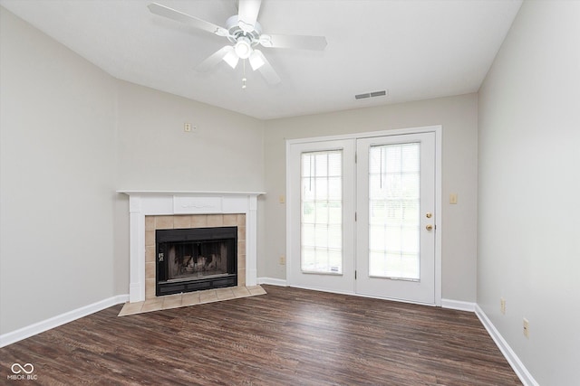 unfurnished living room featuring ceiling fan, a tile fireplace, wood finished floors, and visible vents