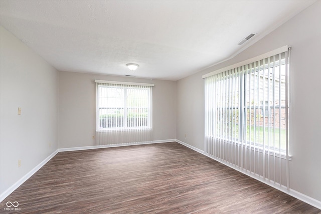 empty room featuring dark wood-type flooring, baseboards, and visible vents