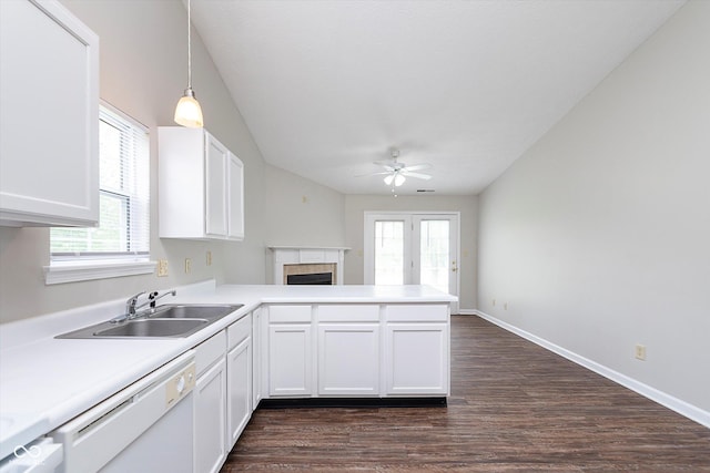 kitchen featuring a peninsula, white dishwasher, ceiling fan, a tiled fireplace, and a sink