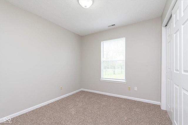 unfurnished bedroom featuring baseboards, visible vents, carpet, and a closet