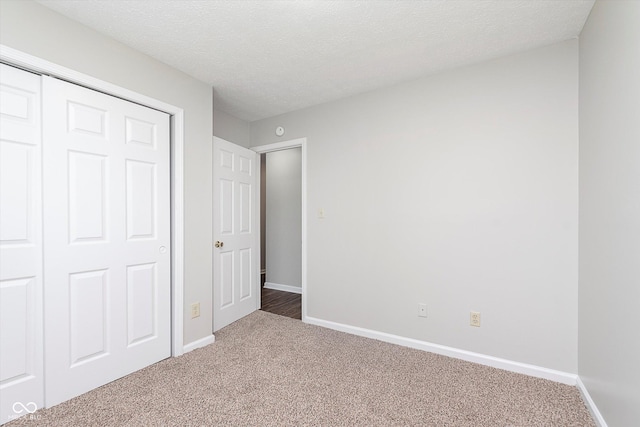 unfurnished bedroom with baseboards, carpet, a closet, and a textured ceiling