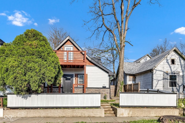 257 N Tacoma Ave, Indianapolis, IN 46201 - rear view of house with stone siding, a fenced front yard, and a balcony