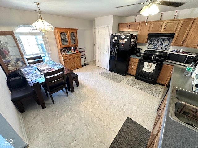 kitchen with a sink, black appliances, light floors, a ceiling fan, and hanging light fixtures
