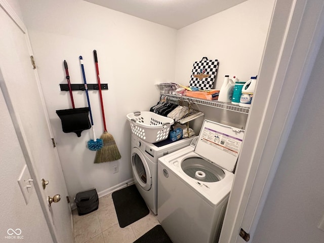 laundry area with baseboards, light tile patterned floors, washing machine and clothes dryer, and laundry area