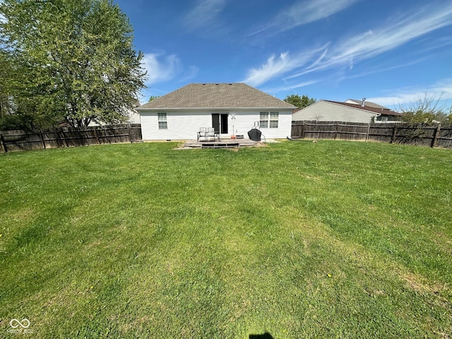rear view of house featuring roof with shingles, a yard, a fenced backyard, and a patio area