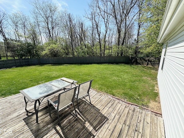 wooden terrace featuring outdoor dining area, a fenced backyard, and a lawn