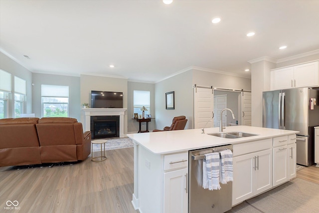 kitchen featuring a barn door, a sink, stainless steel appliances, open floor plan, and light wood-type flooring