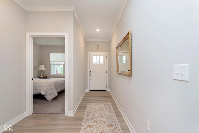 doorway to outside with baseboards, ornamental molding, and light wood-type flooring