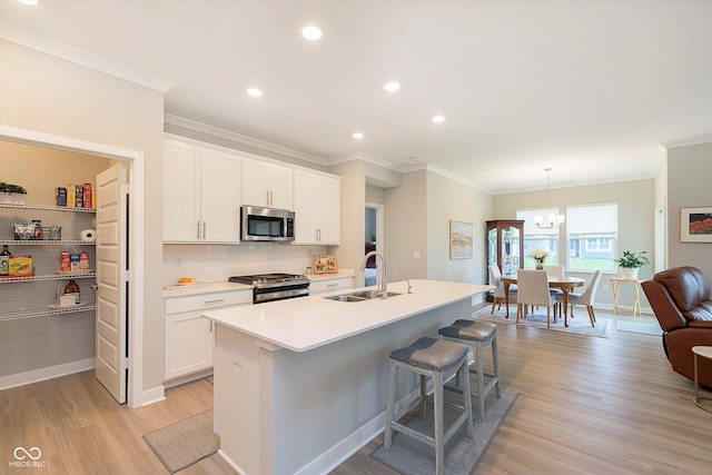 kitchen featuring crown molding, tasteful backsplash, a sink, stainless steel appliances, and light wood-style flooring
