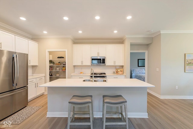 kitchen featuring ornamental molding, a breakfast bar area, light wood-type flooring, a sink, and stainless steel appliances
