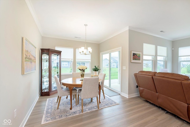 dining space with baseboards, ornamental molding, light wood finished floors, and a chandelier