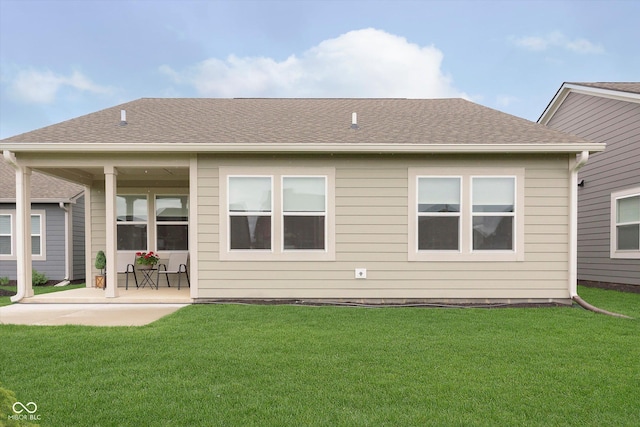 rear view of property featuring a lawn, a patio, and a shingled roof
