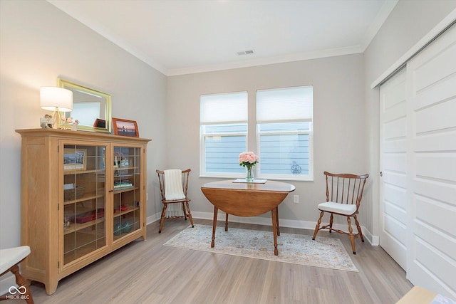 sitting room featuring visible vents, ornamental molding, light wood-style floors, and baseboards