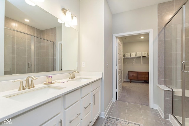 full bath featuring a spacious closet, a shower stall, a sink, and tile patterned flooring