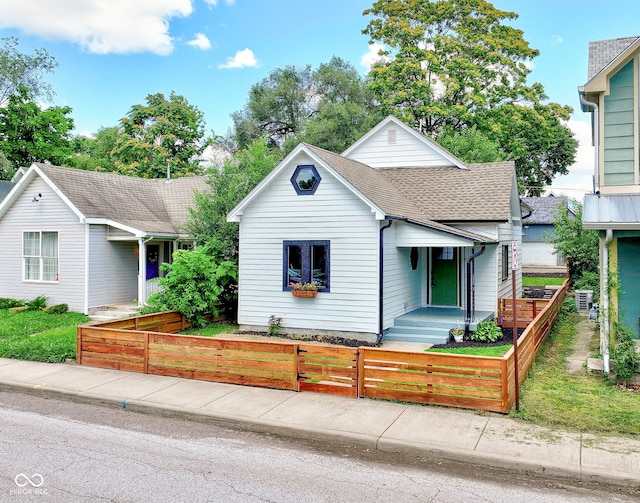 view of front facade with a shingled roof and a fenced front yard