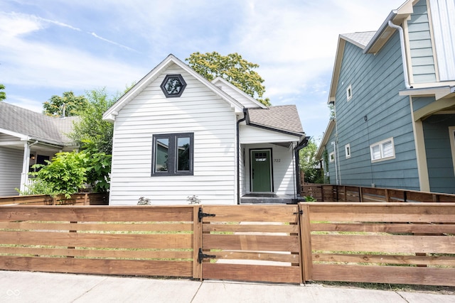 bungalow-style house with roof with shingles, a fenced front yard, and a gate
