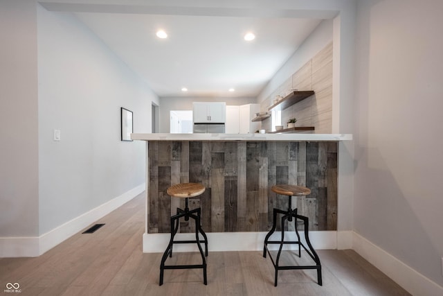 bar with baseboards, light wood-type flooring, visible vents, and recessed lighting