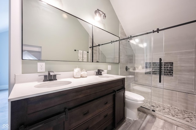 bathroom with a stall shower, toilet, double vanity, and a sink
