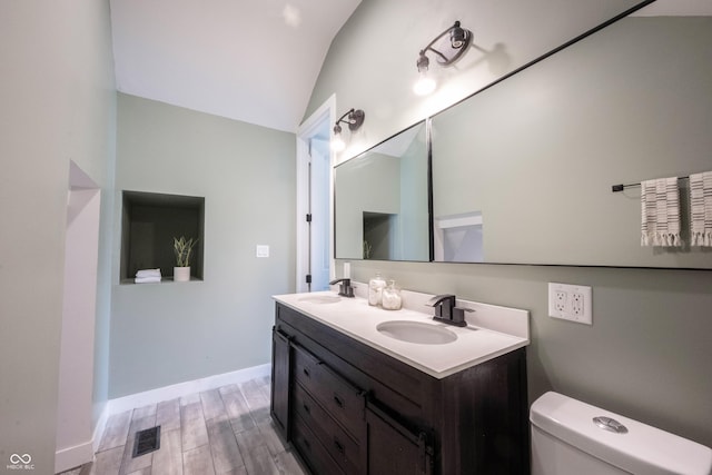 bathroom with toilet, a sink, wood finished floors, and visible vents
