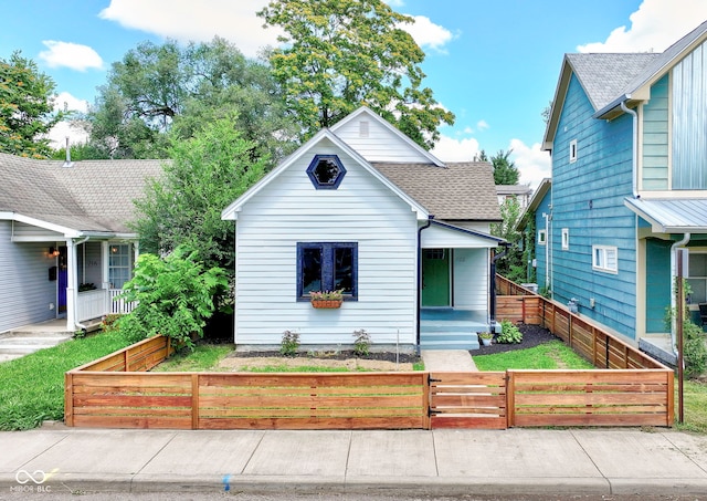 bungalow with roof with shingles, covered porch, a gate, and a fenced front yard