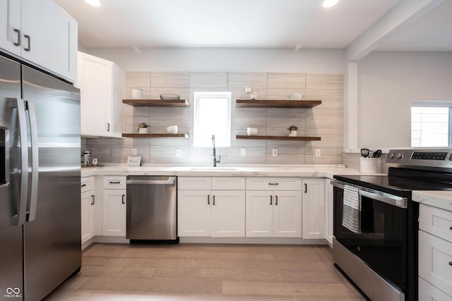 kitchen featuring open shelves, light wood-style floors, appliances with stainless steel finishes, and decorative backsplash