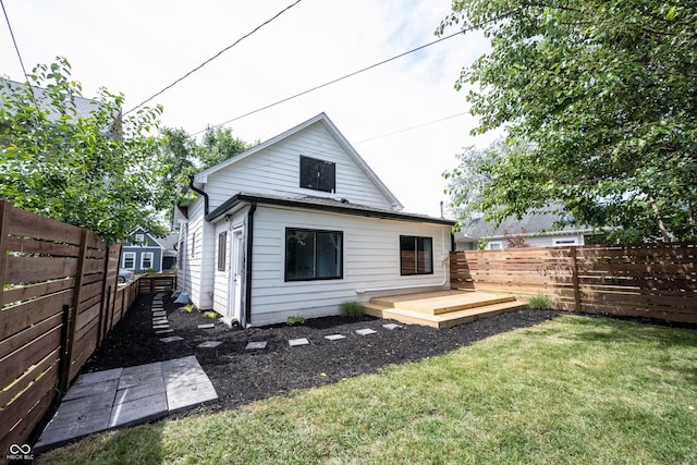 back of house with a lawn, a deck, and a fenced backyard
