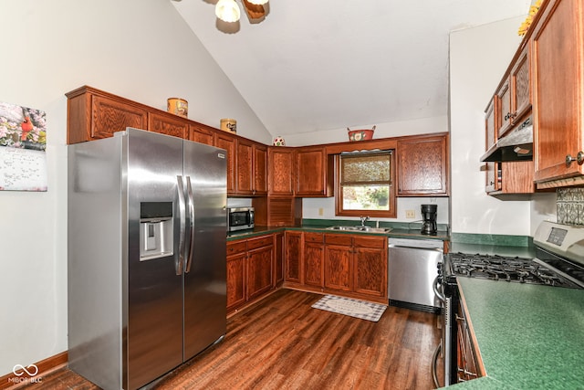 kitchen featuring appliances with stainless steel finishes, dark countertops, vaulted ceiling, a sink, and under cabinet range hood