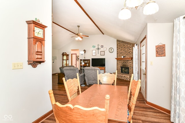dining space with a brick fireplace, a ceiling fan, baseboards, wood finished floors, and vaulted ceiling
