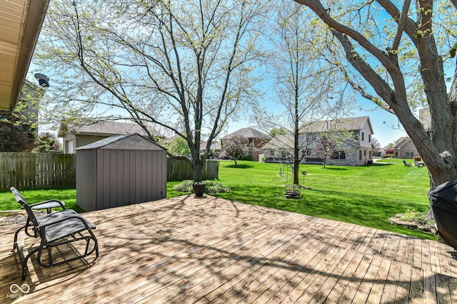 wooden deck featuring a residential view, an outdoor structure, a fenced backyard, a storage unit, and a yard