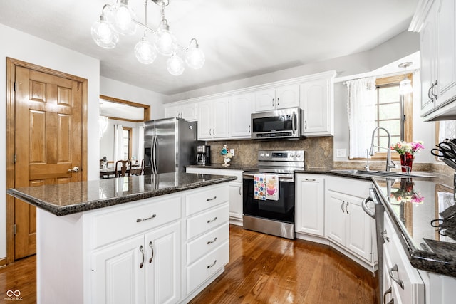 kitchen with a kitchen island, appliances with stainless steel finishes, a sink, and dark wood finished floors