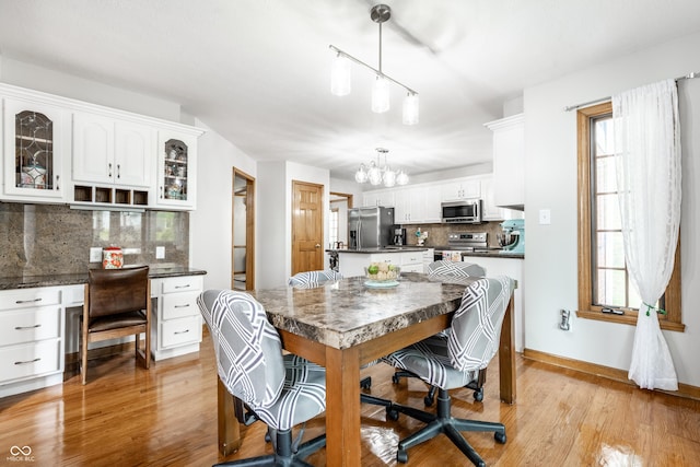 dining space featuring plenty of natural light, light wood-type flooring, and a notable chandelier