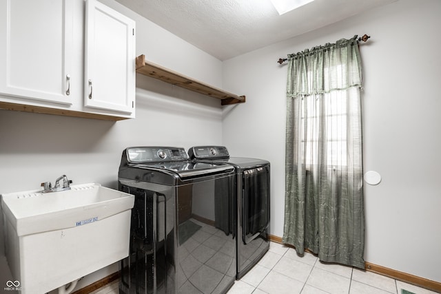 clothes washing area featuring cabinet space, a sink, baseboards, light tile patterned floors, and washer and clothes dryer