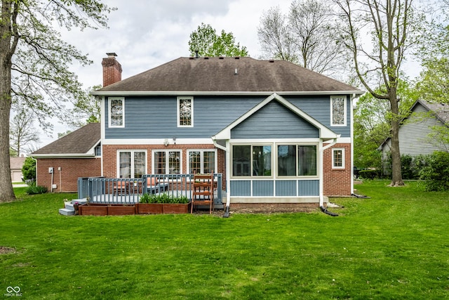 back of house with a deck, a chimney, a sunroom, brick siding, and a lawn