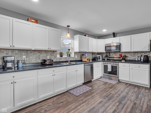kitchen featuring stainless steel appliances, dark countertops, and a sink